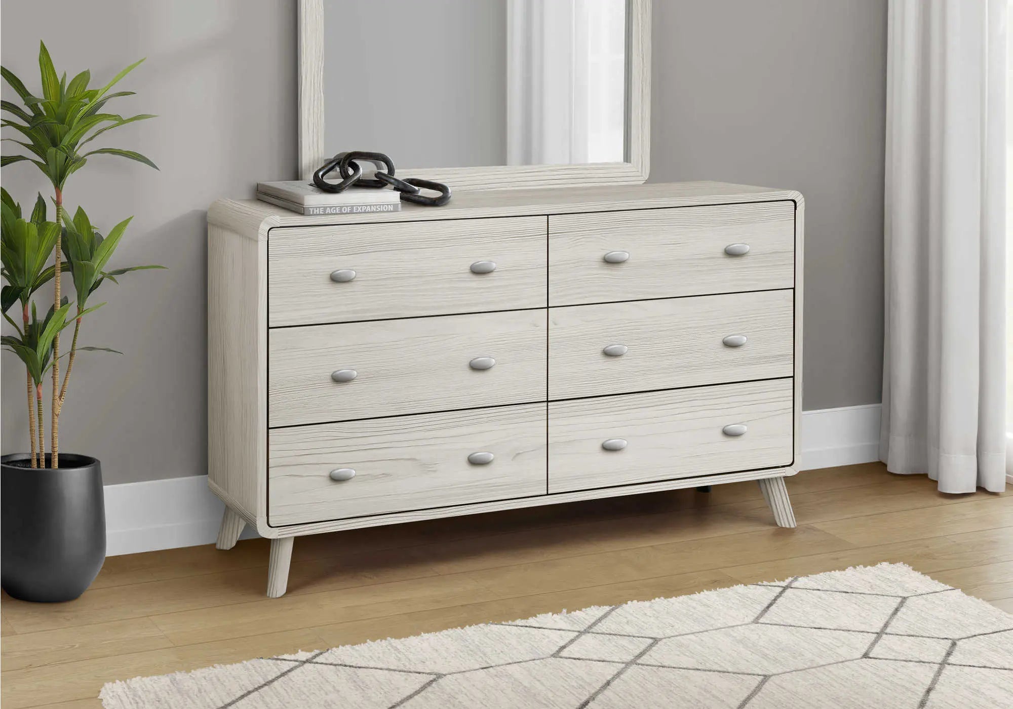 Commode beige en bois avec six tiroirs, miroir assorti et style moderne. Éléments de décoration dans un intérieur élégant.