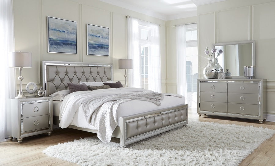 Chambre élégante avec un lit capitonné argenté, une commode moderne et des tableaux muraux, créant une ambiance raffinée. Optimum Plus.