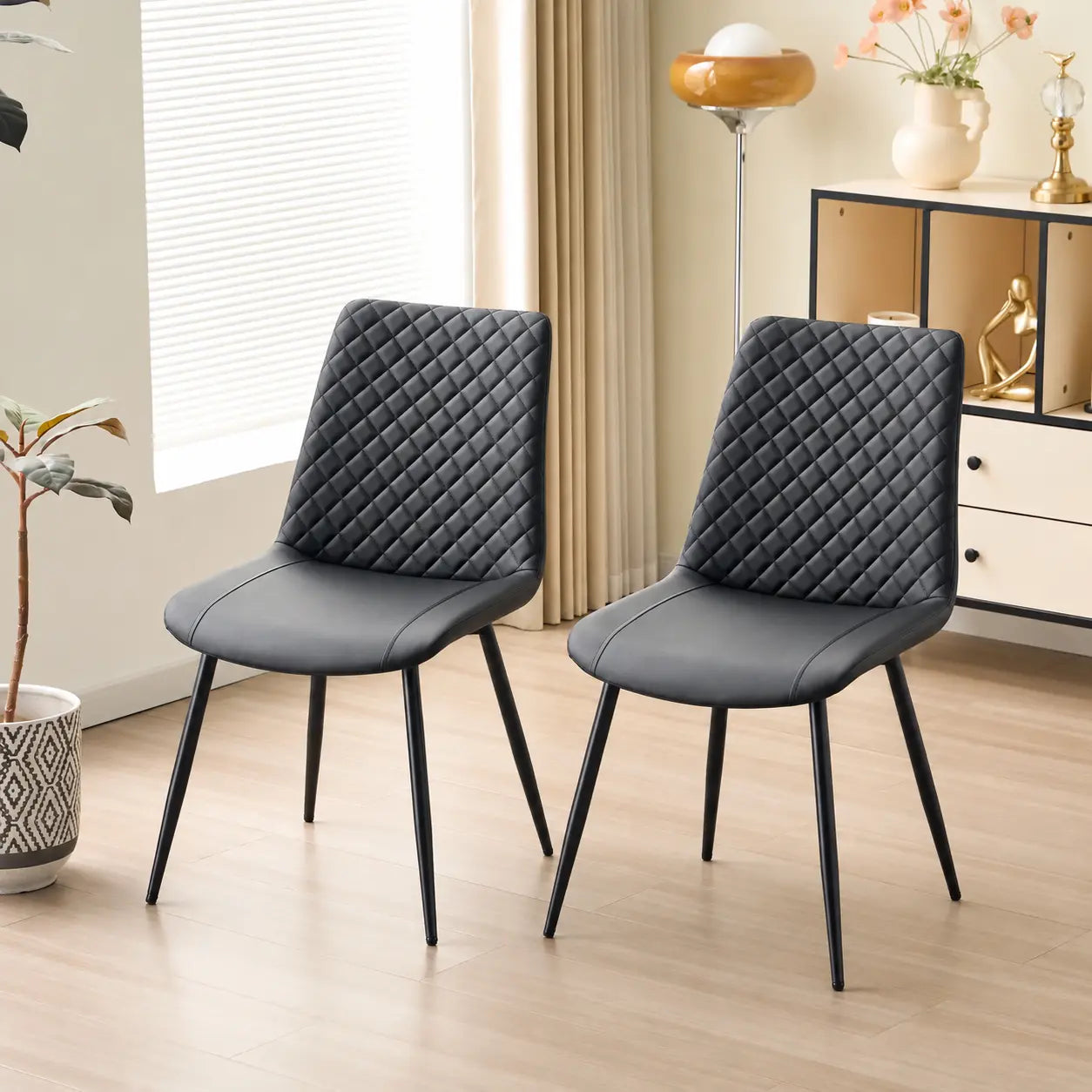 Deux chaises modernes S-2199B avec un siège en PU noir et des pieds en métal.