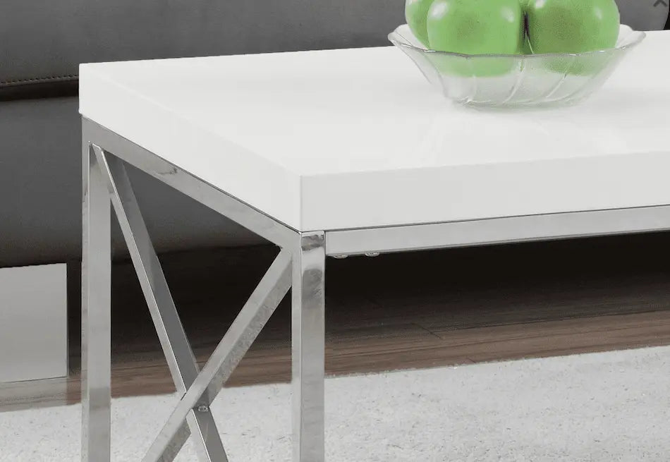 Table basse Optimum Plus moderne avec un plateau blanc brillant et des pieds en métal chromé croisés, offrant une esthétique.