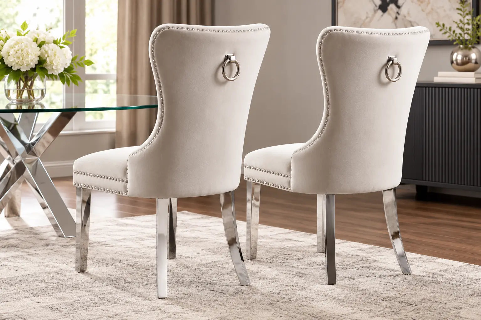 Deux chaises en velours crème avec un cadre en chrome, élégamment conçues pour un intérieur raffiné.