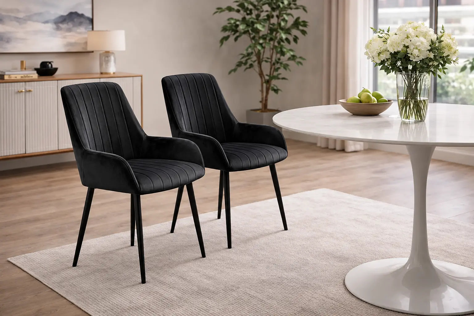 Deux chaises en velours noir au design élégant, placées autour dune table ronde, créent une atmosphère sophistiquée. Optimum Plus.