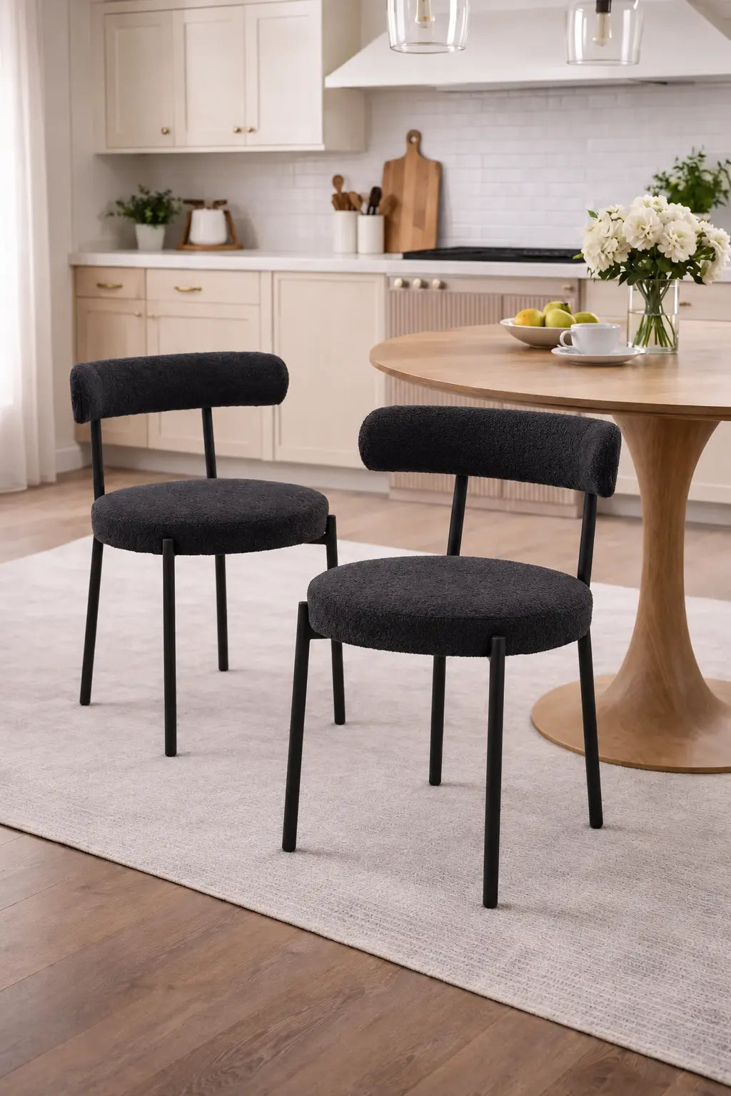 Deux chaises en tissu bouclé noir, au style moderne et élégant, sont placées autour dune table en bois clair.